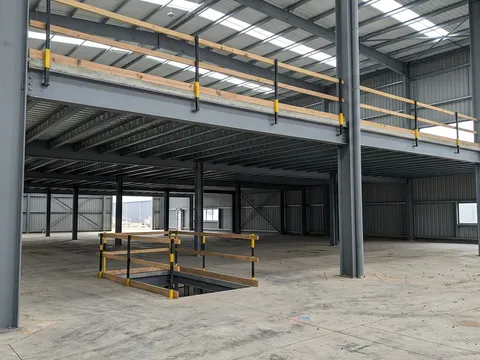 Steel building interior showing mezzanine level with open-web steel joists