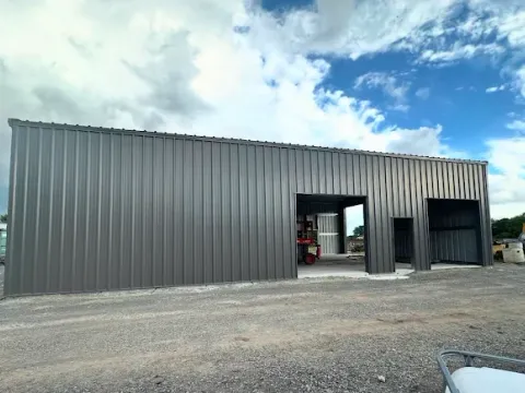 Steel workshop building with overhead door and concrete approach